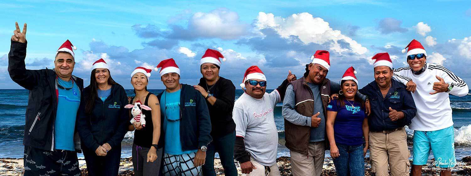The staff of Deep Blue Cozumel with Santa Klaus hats on the beach