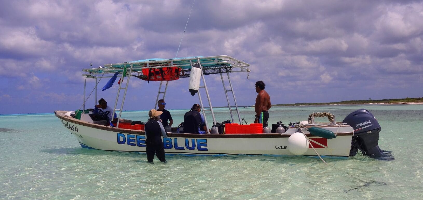Scuba divers preparing on boat in clear turquoise waters